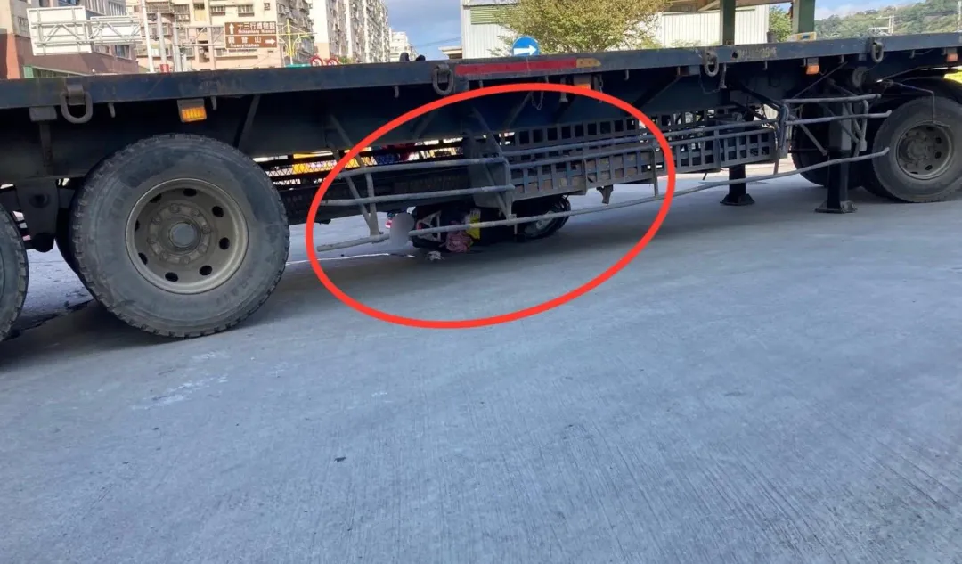 整部機車被拖板車輾過卡在車底。（圖／翻攝畫面）