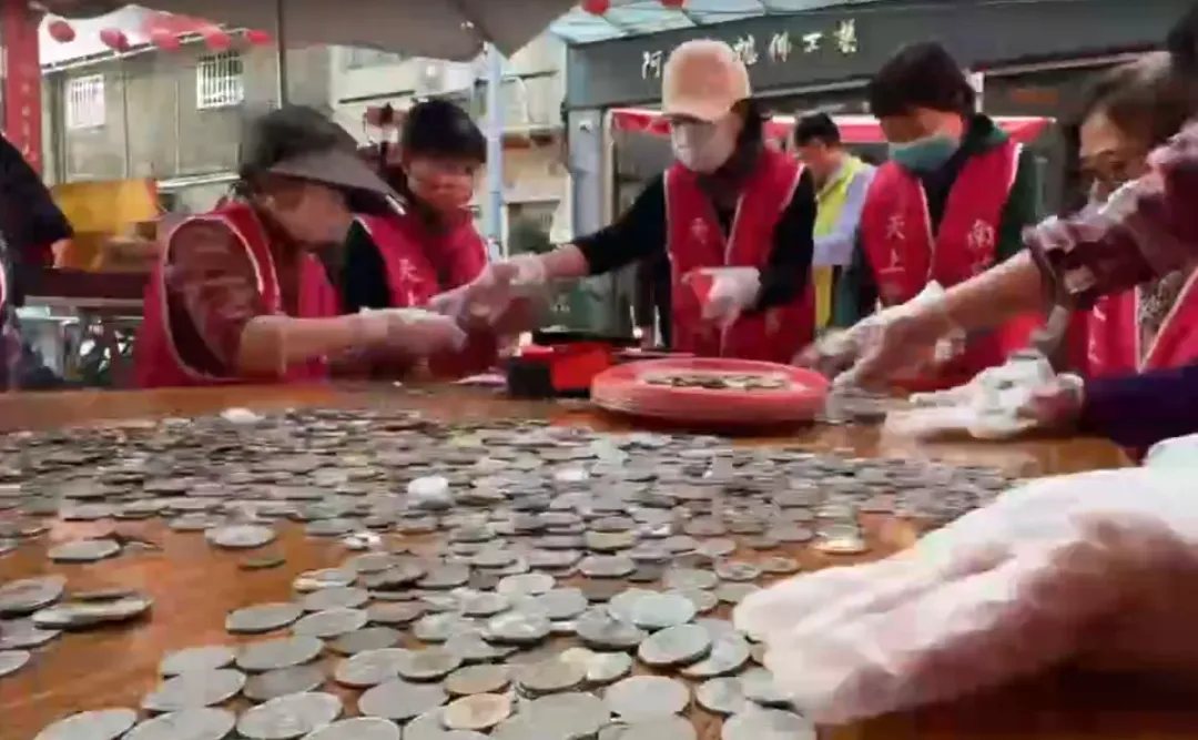 今日南瑤宮志工將功德箱打開,將一箱箱硬幣往桌上倒,清點的桌上,呈現出「硬幣海」的壯觀場面。(圖/中天新聞)
