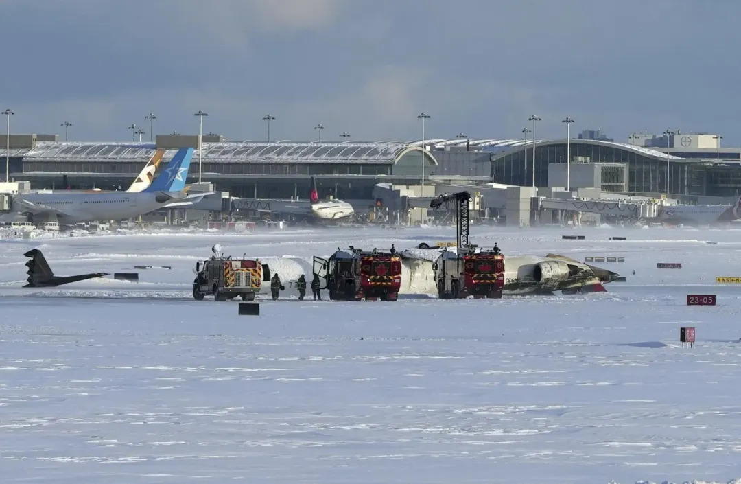 機場消防員在翻覆的達美航空客機附近作業。（圖／美聯社）
