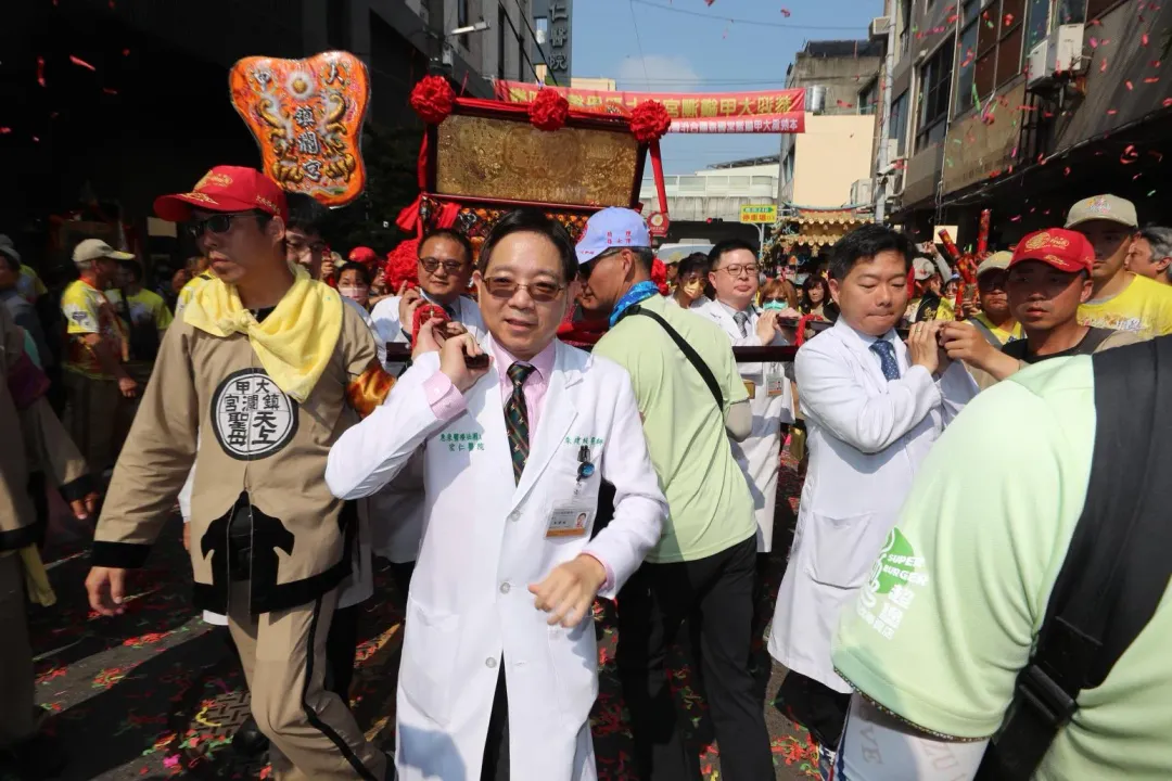 大甲媽回鑾今天上午行經員林,有多位身著白袍的醫護人員也虔誠接駕扛轎,為患者祈福。(圖/宏仁醫院提供)