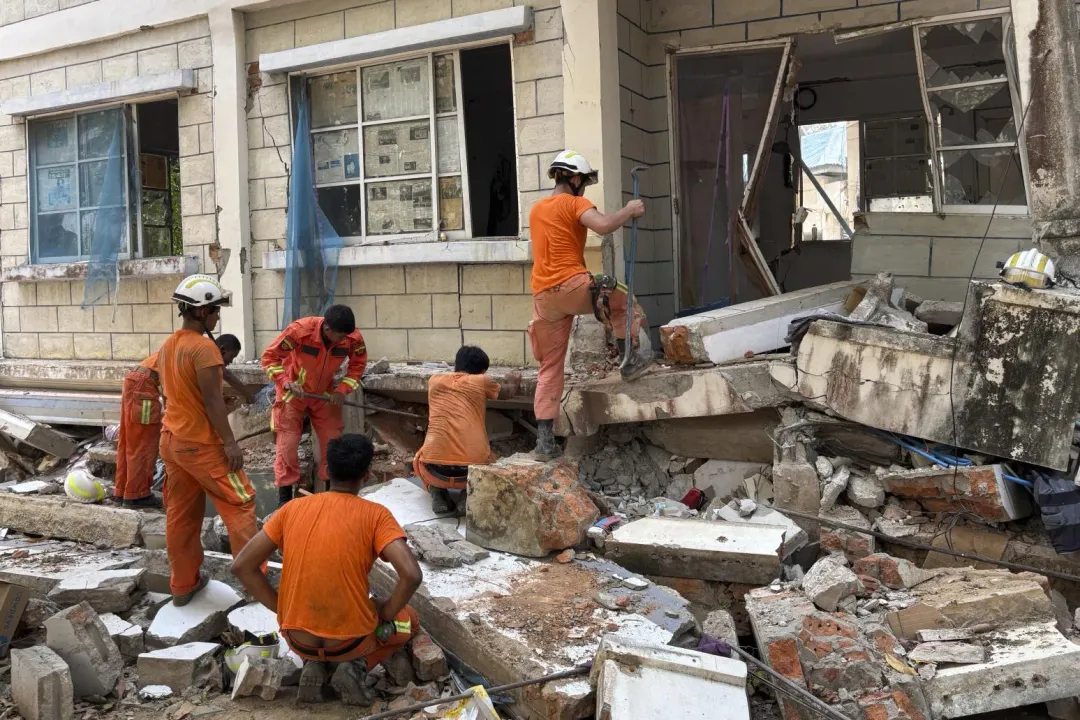 消防員在奈比多一棟公務員居住的受損建築物中，尋找罹難者的物品。（圖／美聯社）