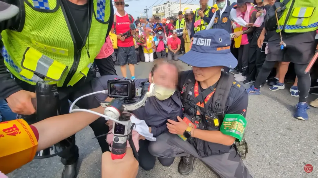 女子連續用力磕頭好幾次,額頭碰出傷痕,周圍工作人員和警察上前攙扶女子。(圖/翻攝自YouTube@baishatun_tv)