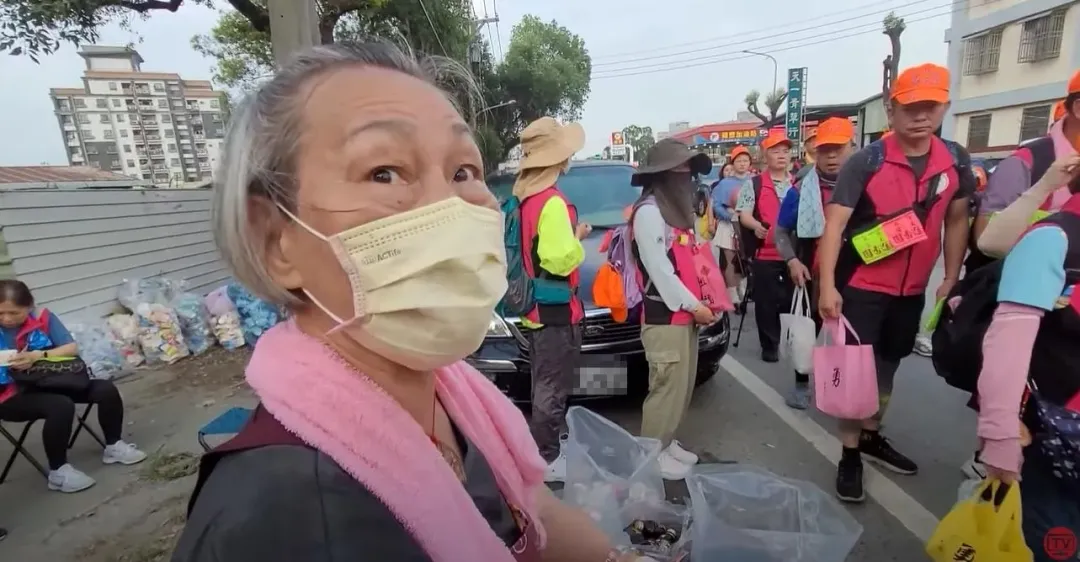 年約70歲的老婦人默默地拿著垃圾袋，主動幫忙替香燈腳們回收沿途的垃圾。（圖／翻攝自白沙屯媽祖網路電視台）