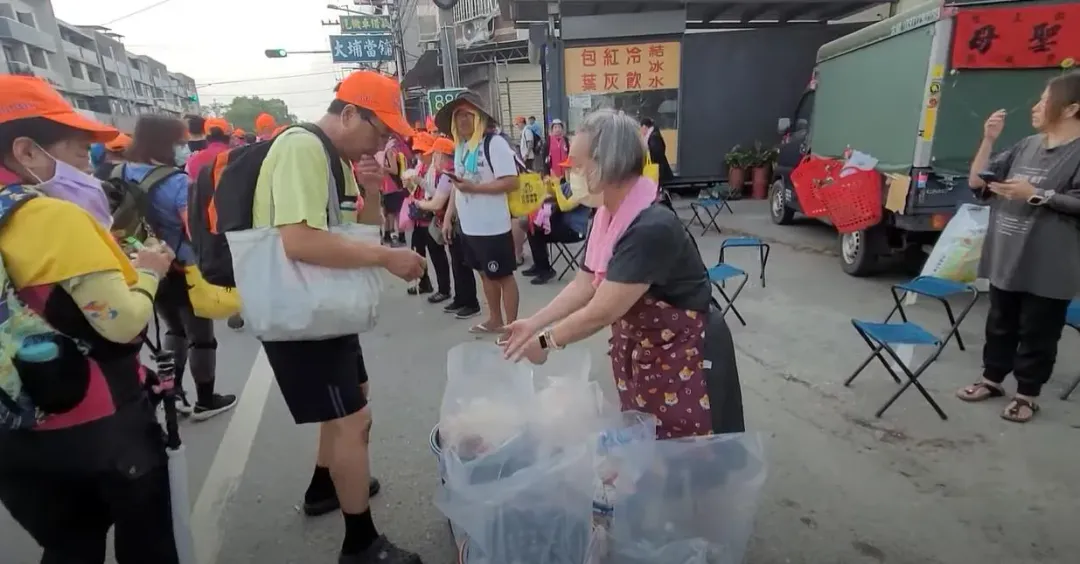 年約70歲的老婦人默默地拿著垃圾袋，主動幫忙替香燈腳們回收沿途的垃圾。（圖／翻攝自白沙屯媽祖網路電視台）