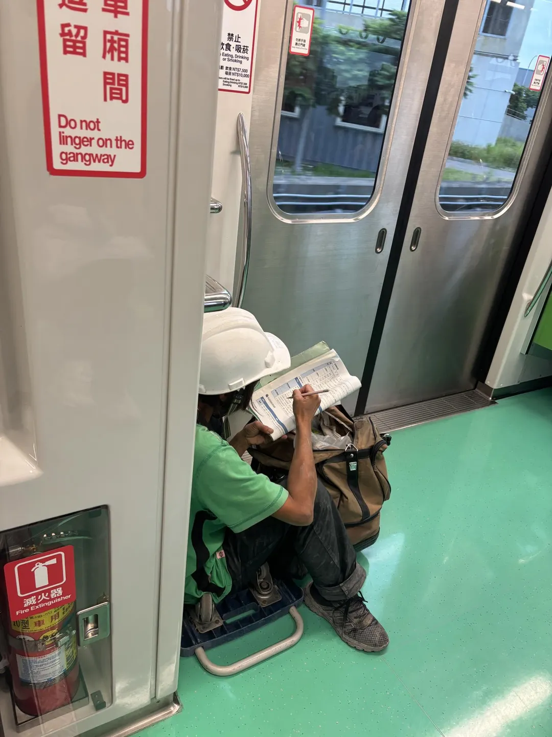 頭戴工人帽的女子蹲在捷運車廂內看書,且認真的用筆劃重點。(圖/翻攝自李威立臉書)