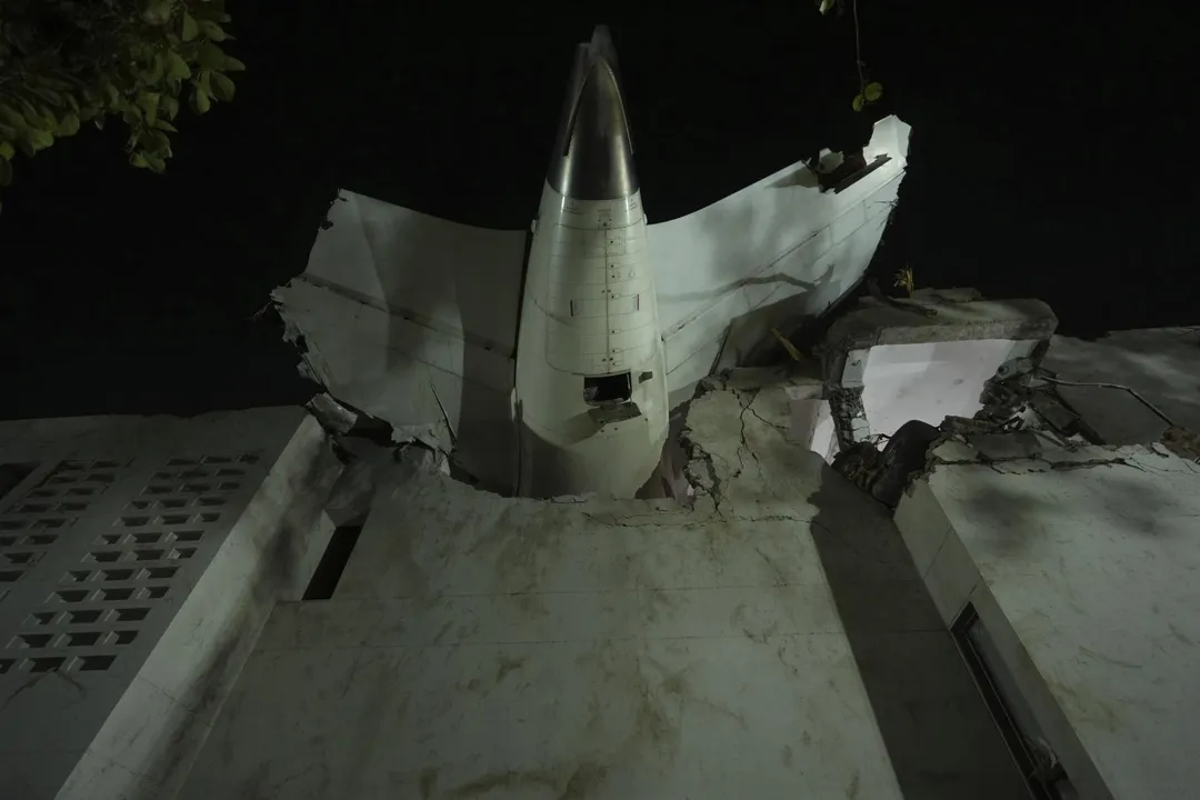 印航墜毀客機的機尾卡在一棟建築物屋頂。(圖/美聯社)