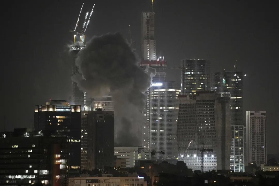 飛彈擊中特拉維夫的一棟建築後,冒出滾滾濃煙。(圖/美聯社)