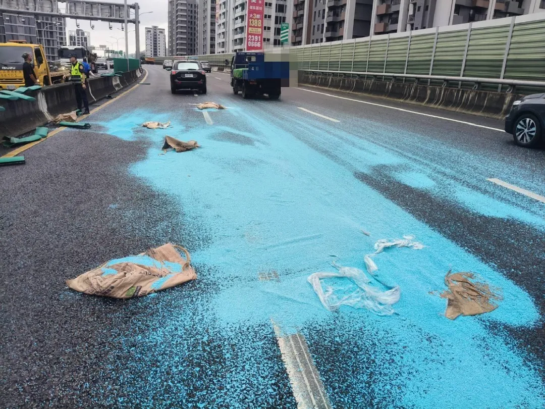 大貨車打滑自撞中央分向護欄,車上載的藍色塑膠微粒散落一地。(圖/翻攝畫面)