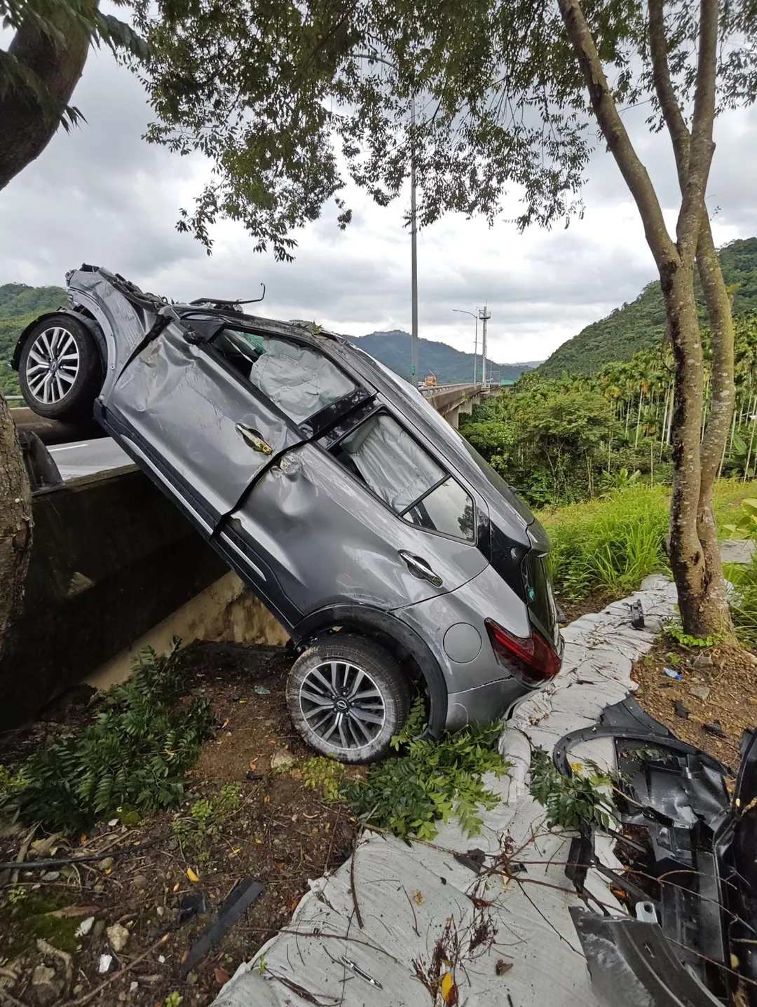 國道六號一輛灰色休旅車追撞前方銀色轎車後衝撞護欄,車輛懸掛在護欄外。令人意外的是,肇事駕駛不僅未查看車況,反而在路肩盤腿打坐。(圖/翻攝畫面)