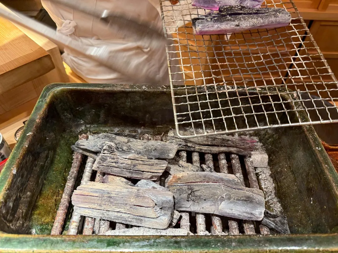餐食結束後，料理長又往爐內添加菊花木炭。（圖／黃宏輝提供）