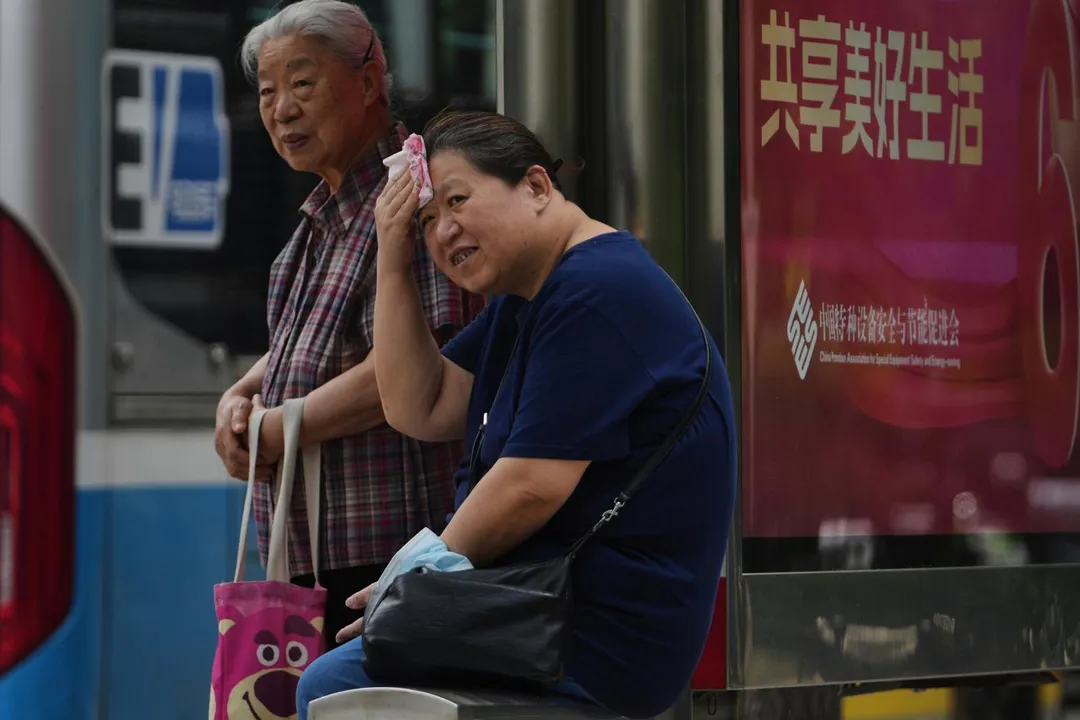 圖為7月14日，一名女子在北京等公車時以手帕擦汗。（圖／美聯社）