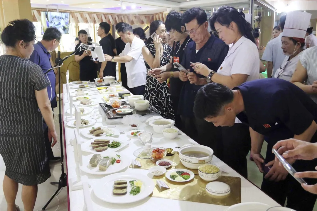 2025年7月15日平壤黎明大街美食節會館,人們圍觀展出的包括狗肉在內的各種美食。(圖/美聯社)