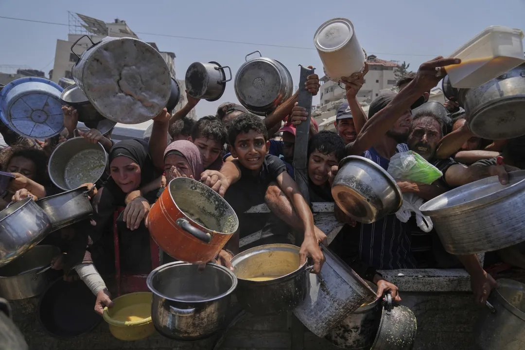 巴勒斯坦人在加薩北部的一個社區廚房爭先恐後地領取食物。（圖／美聯社）