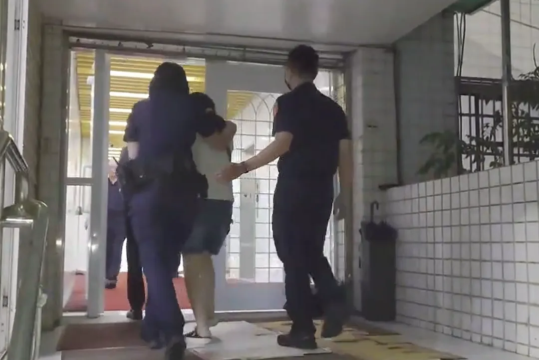 保母在員警的陪同下進入派出所，配合調查。（圖/翻攝畫面）
