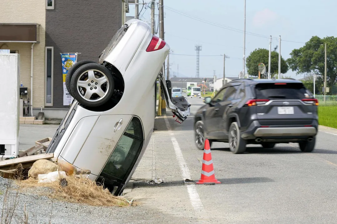 大雨過後，一輛汽車被困在熊本縣八代市的溝渠裡。（圖／美聯社）