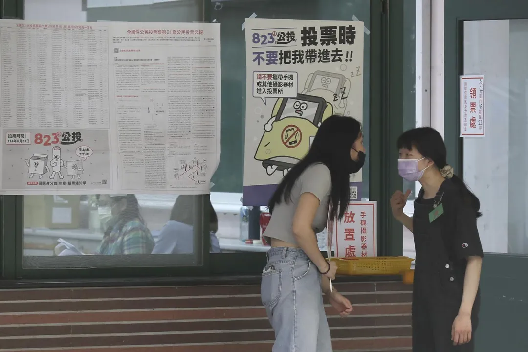圖為8月23日,2名工作人員在台北投票所進行交談。(圖/美聯社)