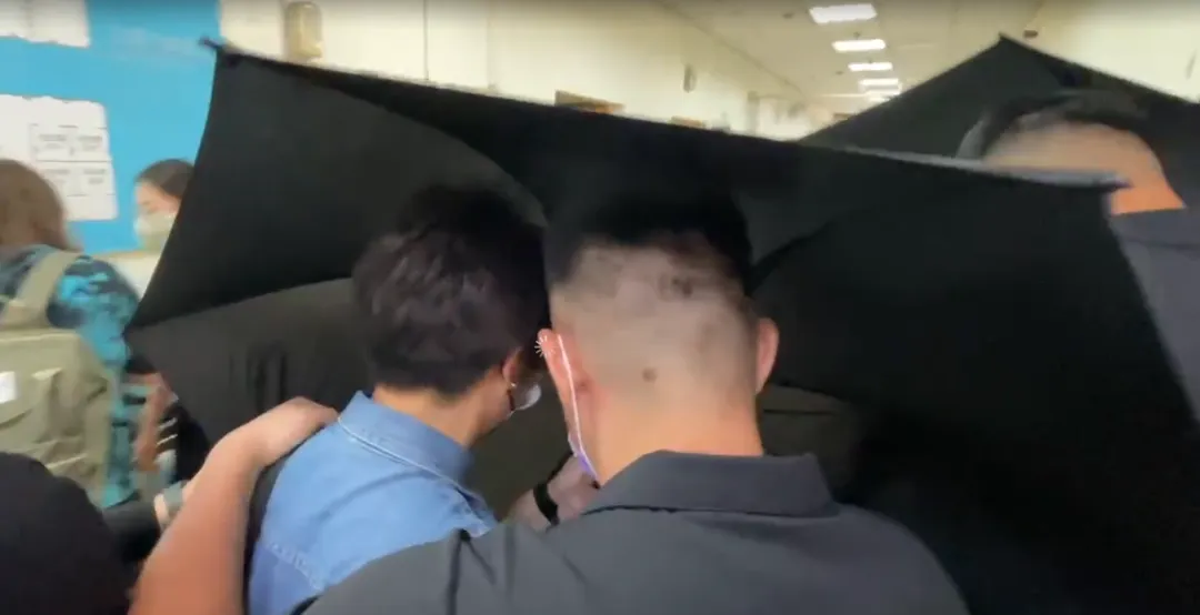 羅男家屬前往高雄市立殯儀館確認相關細節時，全程低頭不發一語，在殯葬人員的協助下，以黑傘遮擋，快步通過守候的媒體。（圖／中天新聞）