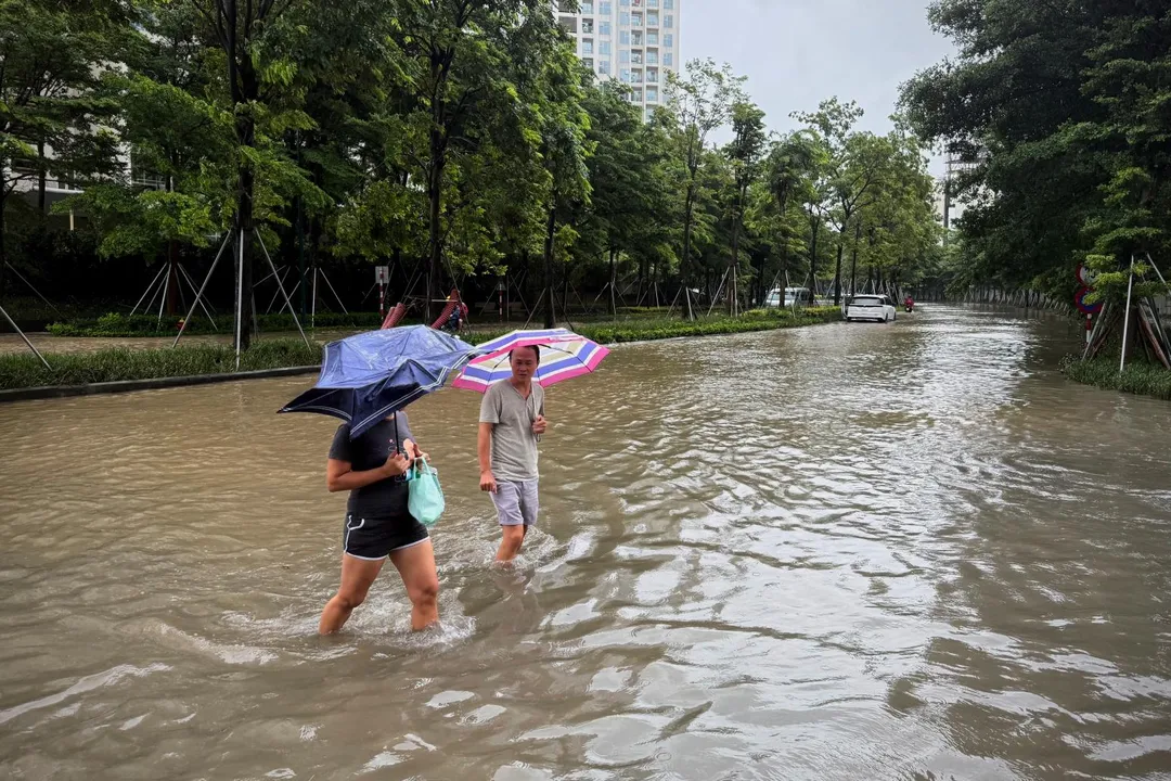 越南河內民眾穿越颱風造成的淹水街道。（圖／美聯社）（圖／美聯社）