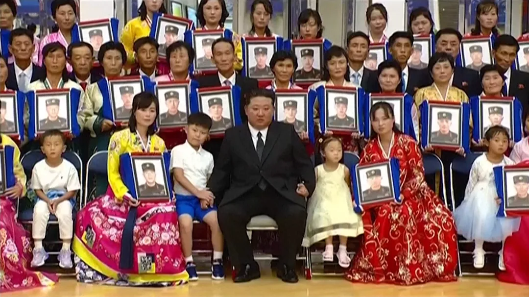 金正恩與手持陣亡將士照片的家屬合影。（圖／路透社）