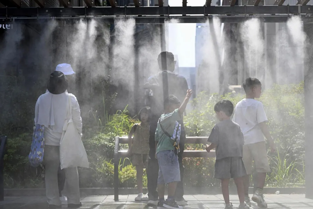 8月31日，遊客在日本東京的噴霧裝置下消暑。（圖／美聯社）