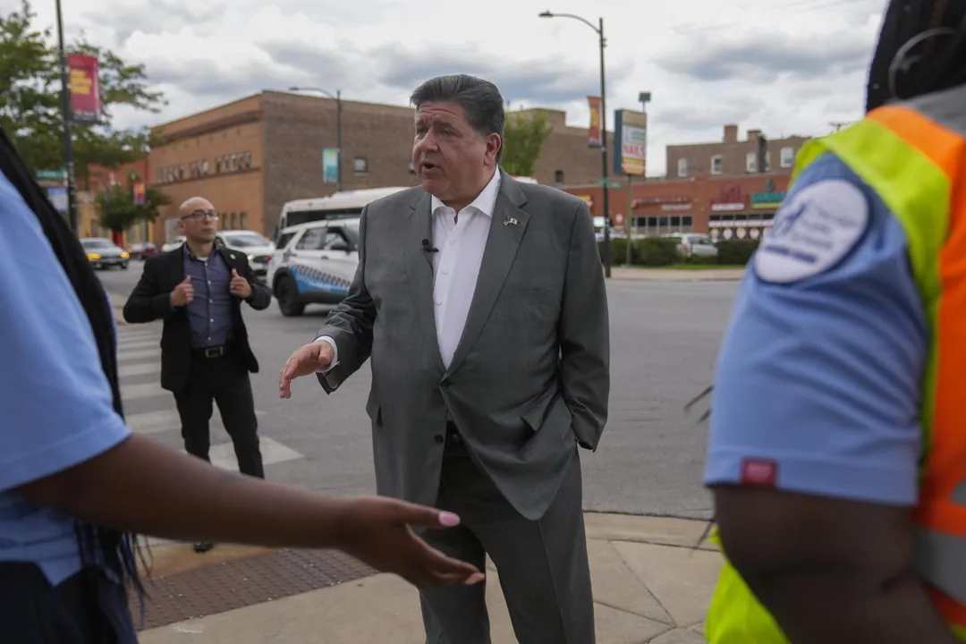 8月27日,伊利諾州州長普利茲克在芝加哥社區與2名警衛交談。(圖/美聯社)