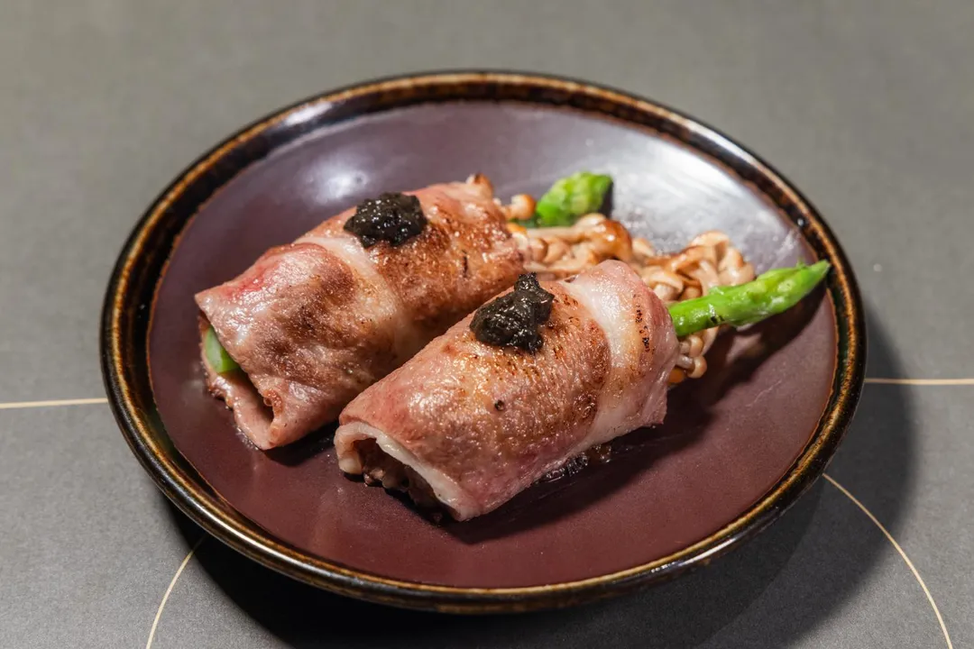 _台北旭集三間門市推出期間限定料理〈炙饌松露A5和牛卷〉，是利用鐵板煎炙讓和牛香氣提升，再將爽脆鮮蔬一起捲入，和牛油脂與爽口蔬果相互平衡下，點上松露醬，口感富有層次與深度，於午晚餐期間供應。（圖/饗賓集團提供）