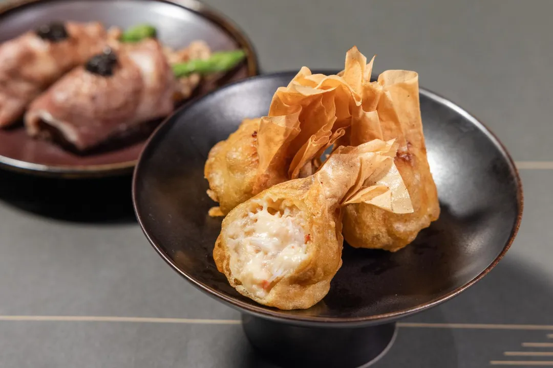 台北旭集三間門市推出期間限定料理〈香穗雪蟹茶巾揚〉，內餡除了雪蟹，還加入龍蝦沙拉、酪梨、馬鈴薯泥及奶油玉米醬，以千層豆皮包覆，下鍋炸至金黃，外表金黃酥脆、內裡滑順香甜，讓人驚喜。（圖/饗賓集團提供）