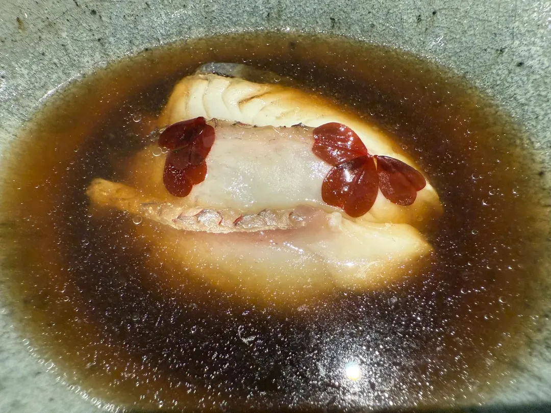 真鯛皮下脂肪出油，在牛肝蕈菇清湯中呈現露珠狀的油點。（圖／黃宏輝提供）