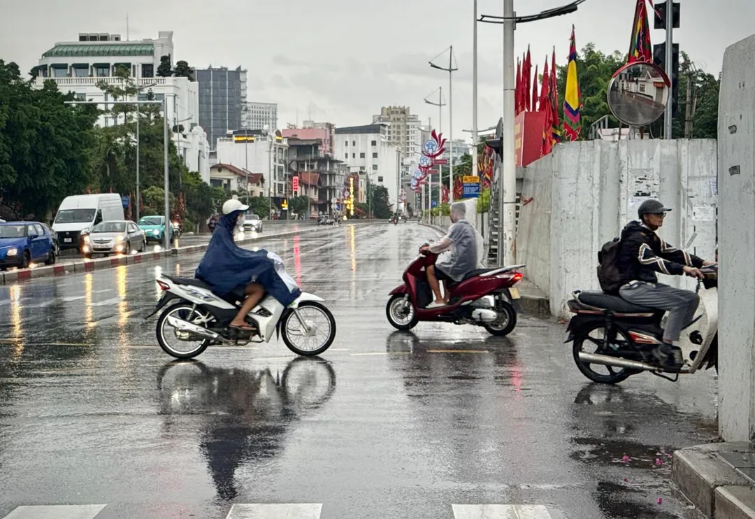 越南河內的民眾冒雨出行。（圖／美聯社）