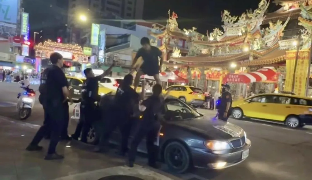 男子情緒失控站在車頂上叫囂與警對峙。(圖/翻攝畫面)