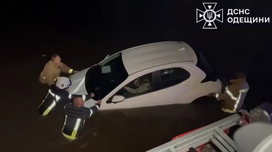 消防員將汽車推過洪水。（圖／路透社）
