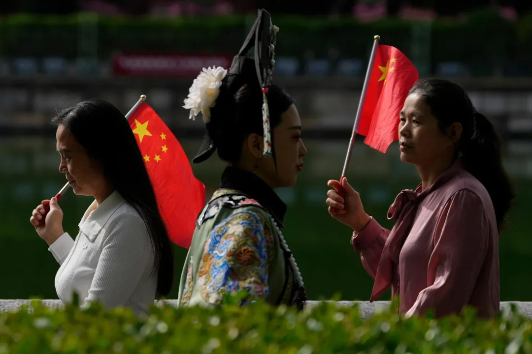 圖為大陸「十一」長假期間，手持五星旗的民眾在北京故宮外。（圖／美聯社）