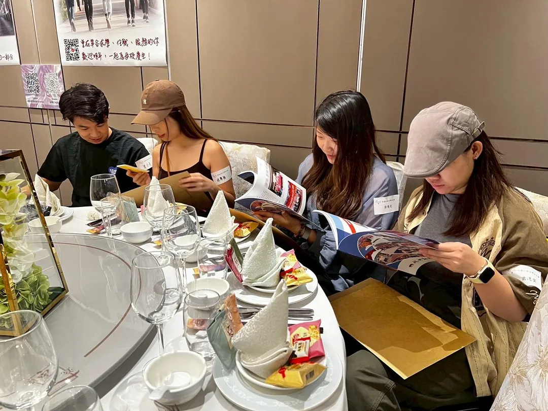 香港校友翻閱校友會總會精心製作的會刊《我世新來的》，回顧母校近年榮耀時刻與校園發展成果。（圖／世新大學提供）
