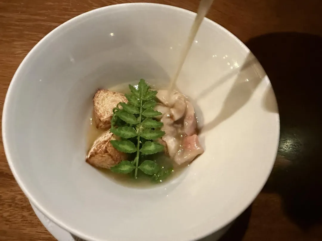需將帶柑橘味的老母雞澄清湯緩緩倒入餐點。（圖／黃宏輝提供）