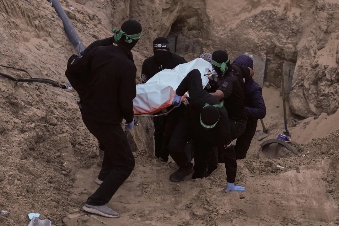 哈瑪斯戰士從地道中出現，抬著一具以白色塑膠袋包裹的遺體。（圖／美聯社）