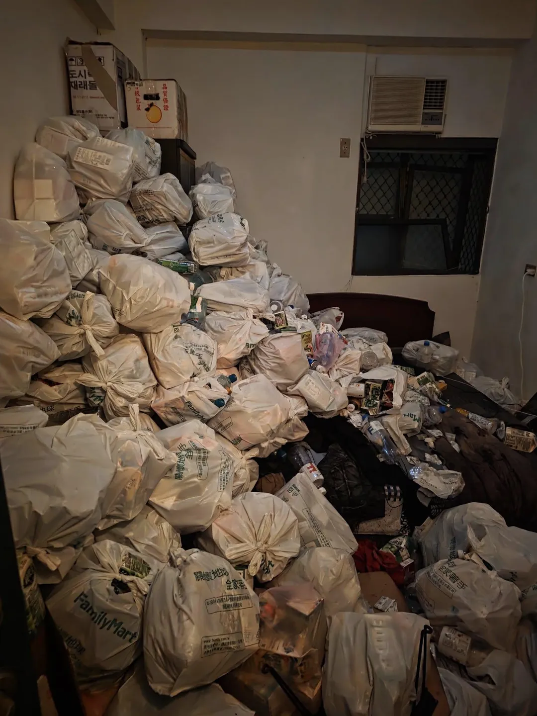 該套房內垃圾袋堆疊至接近天花板，多數垃圾袋為超商購物袋，飲料瓶罐散落各處。（圖/翻攝臉書福和里里長-林寅利【阿利里長】）