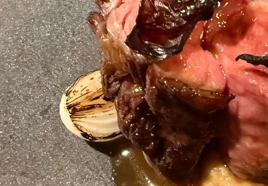 牛肉左側擺放炙燒醃漬洋蔥，辛辣感變成溫和與甜味。（圖／黃宏輝提供）