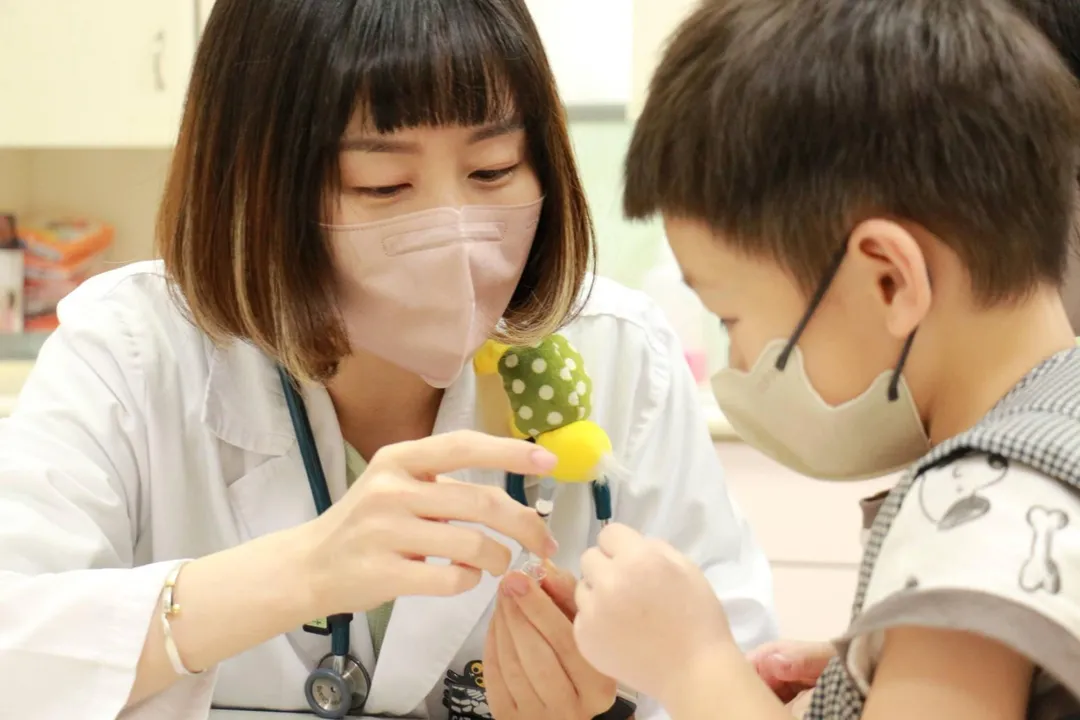嘉基醫院兒科醫師蔣欣妤與害怕打針的幼童示範鼻噴式疫苗的使用方式。（圖／嘉義基督教醫院）