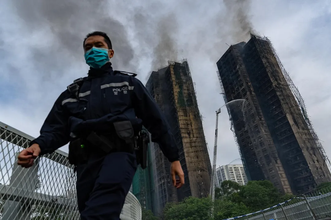 一名香港警察今走過宏福苑火災現場。 (圖/美聯社)