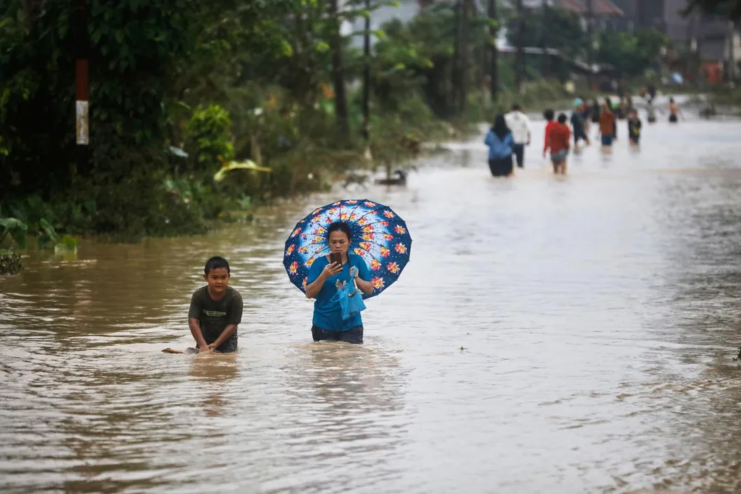 印尼蘇門答臘島近日遭暴雨及土石流侵襲，救難人員今天加緊腳步，趕赴災區將受困在湍急泥流中的居民救出。（圖／美聯社）