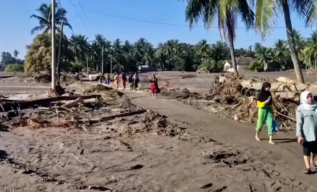 大水沖毀印尼災區的道路，婦女只能徒步走在乾涸泥道上。（圖／路透社）