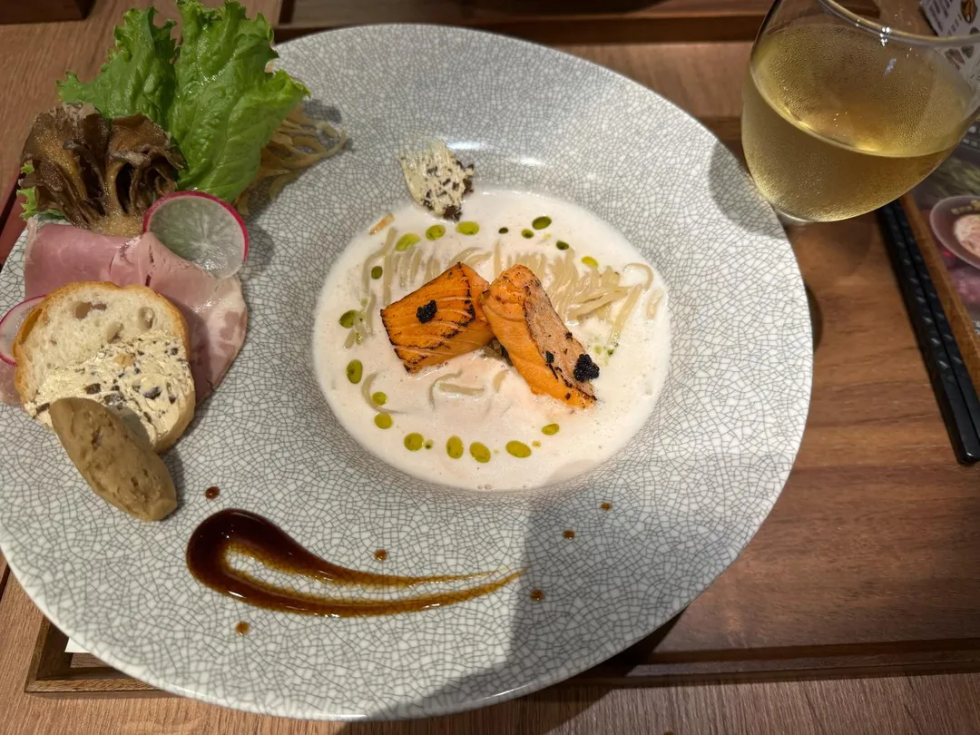 牛肝蕈鮭魚拉麵附上白酒，炙燒鮭魚、魚子醬是這碗法式拉麵的主角。（圖／黃宏輝提供）