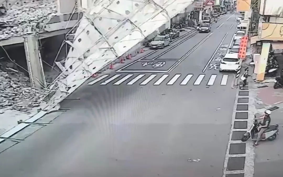 監視器畫面左側的鷹架無預警倒向馬路，畫面右側的人車急忙躲避。（圖／中天新聞）