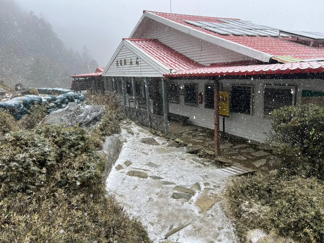 台東嘉明湖國家步道26日中午起飄雪，嘉明湖山屋前落下點點白雪。（圖／嘉明湖熊出沒企業社提供）