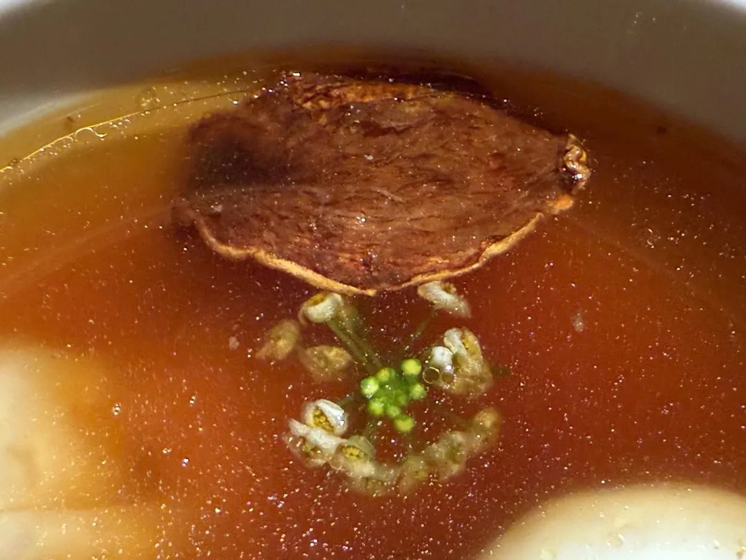 黑麻油煸過的老薑片、當歸花和枸杞飄在澄清湯上,滋味豐醇回甘。(圖/黃宏輝提供)