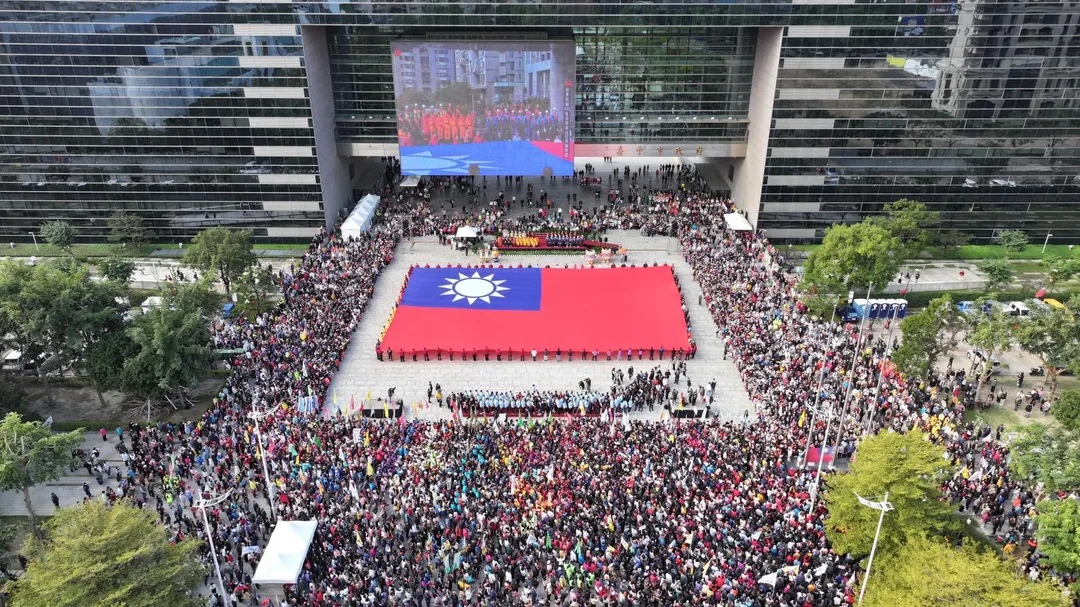 台中市政府今（1）日在府前廣場舉行元旦升旗典禮，88名救災與復原英雄共同展開全國最大巨幅國旗，場面震撼。（圖/台中市府提供）