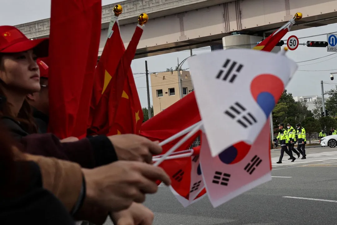 南韓總統李在明4日起訪問中國大陸。圖為釜山機場附近支持民眾揮舞中韓國旗。（圖／路透社）