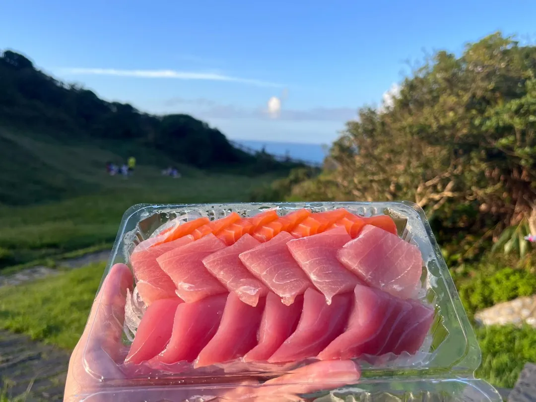 坐在草地上，在海風的吹拂下享用一份生魚片，能感受到無與倫比美味。（圖／記者鄭緯浩攝）
