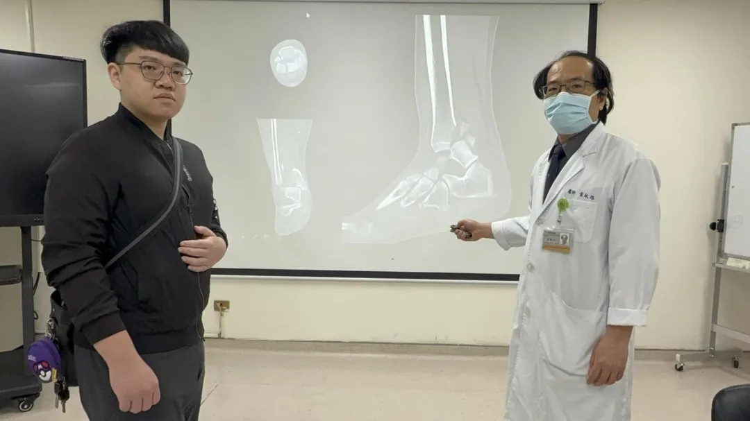 ️黃敏旭醫師（右）說明賈先生（左）下班途中車禍導致腳踝粉碎性骨折。（圖／台中醫院）