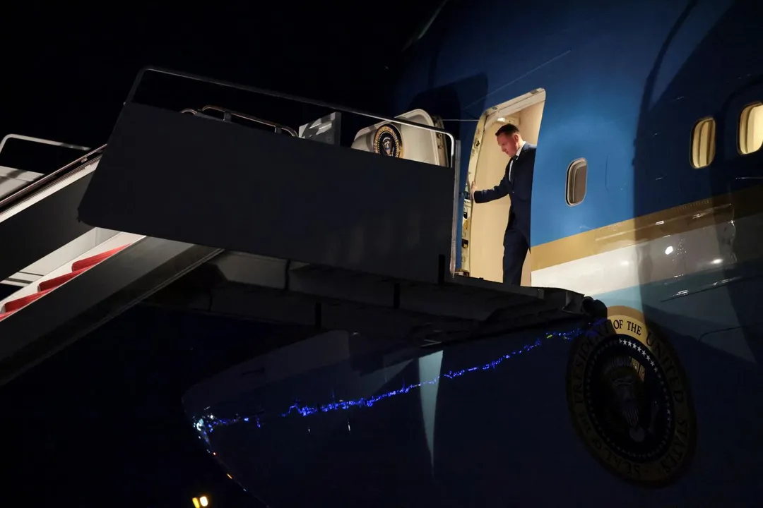 川普搭乘的空軍一號20日折返安德魯斯聯合基地後，工作人員正在安排他下機。 （圖／路透社）